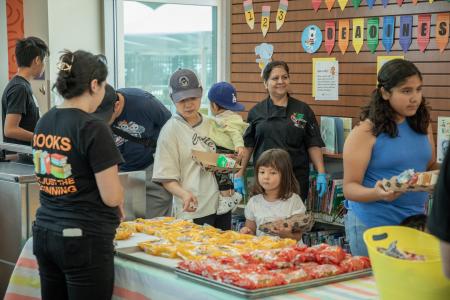 Photo of Lunch at the Library program at Tustin Library. Patrons wait in line to select food for lunch.